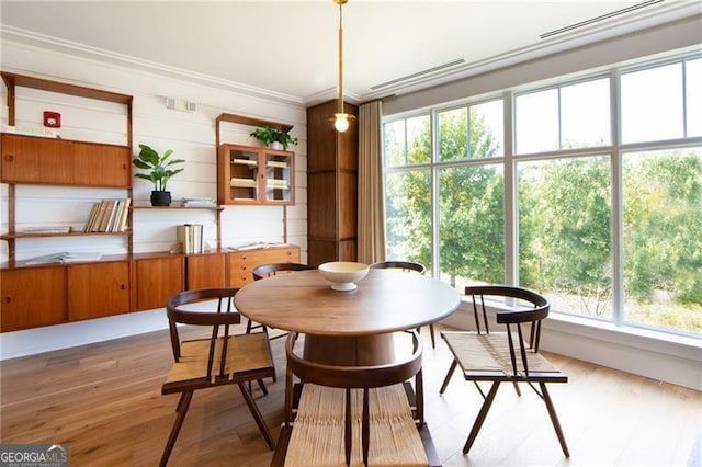 dining space with crown molding and light hardwood / wood-style flooring