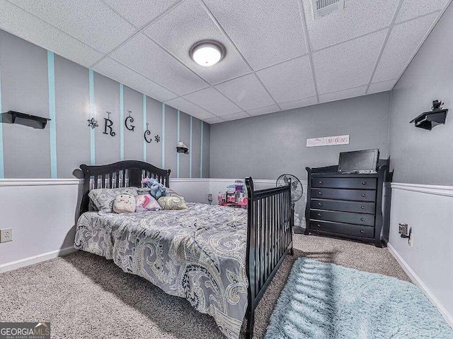 carpeted bedroom featuring a drop ceiling