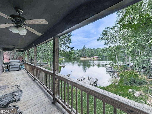 wooden terrace with grilling area, a water view, and ceiling fan