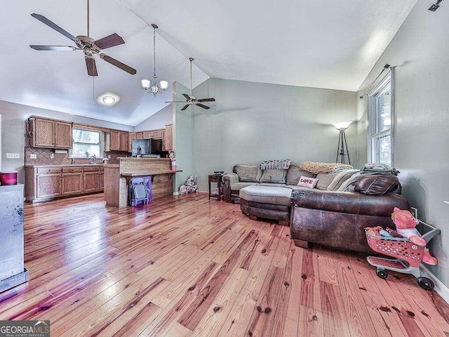 living room with high vaulted ceiling, light wood-type flooring, and ceiling fan with notable chandelier