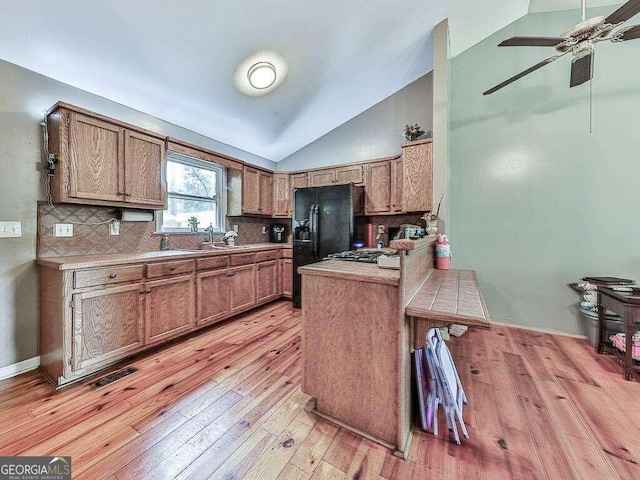 kitchen featuring visible vents, ceiling fan, light wood-style floors, a peninsula, and vaulted ceiling