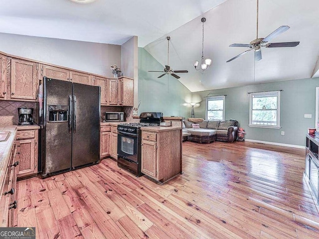 kitchen with light hardwood / wood-style floors, black appliances, tasteful backsplash, and decorative light fixtures