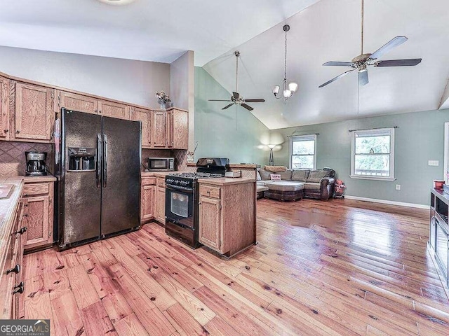 kitchen featuring a ceiling fan, a peninsula, black appliances, light wood-style flooring, and high vaulted ceiling