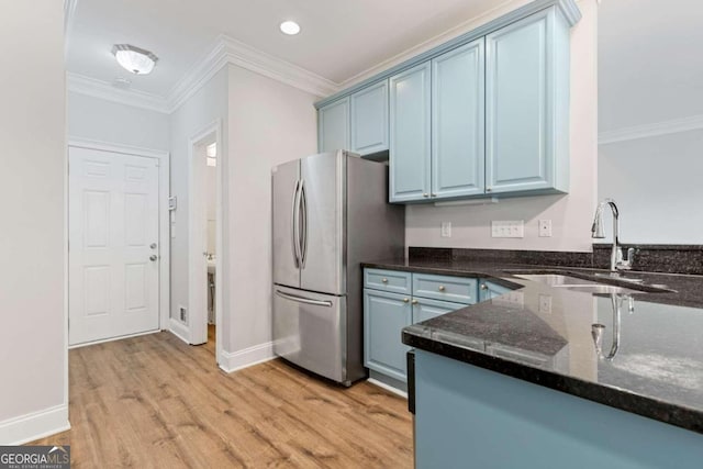 kitchen with sink, light hardwood / wood-style flooring, ornamental molding, blue cabinetry, and stainless steel refrigerator