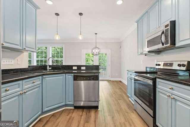 kitchen featuring ornamental molding, stainless steel appliances, sink, decorative light fixtures, and a chandelier