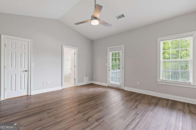 empty room featuring dark wood-type flooring, a healthy amount of sunlight, and vaulted ceiling