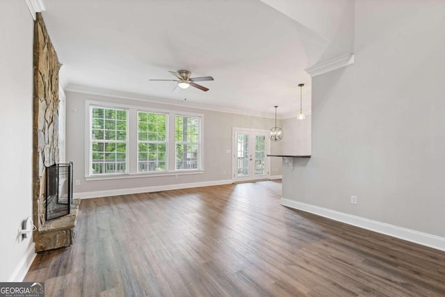 unfurnished living room featuring ceiling fan with notable chandelier, dark hardwood / wood-style flooring, crown molding, and a fireplace