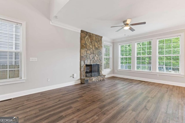 unfurnished living room with ceiling fan, dark hardwood / wood-style flooring, a stone fireplace, and ornamental molding