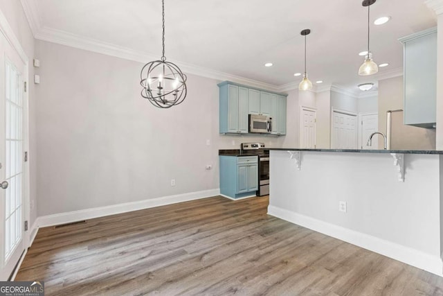 kitchen featuring a kitchen bar, pendant lighting, dark hardwood / wood-style floors, and appliances with stainless steel finishes