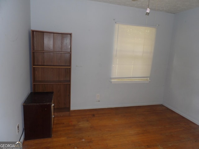 empty room featuring a textured ceiling and dark wood-type flooring