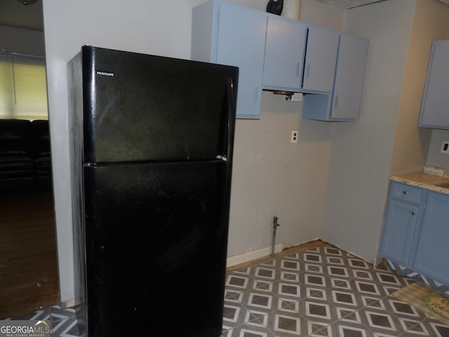 kitchen featuring black refrigerator and blue cabinetry