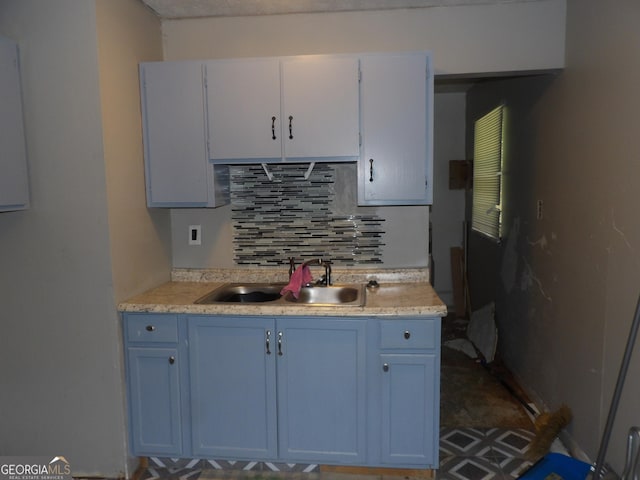 kitchen with decorative backsplash, white cabinets, and sink