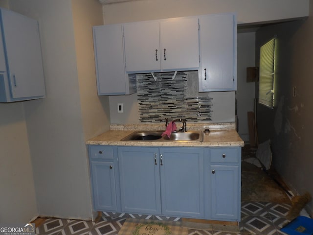 kitchen with decorative backsplash, white cabinetry, and sink