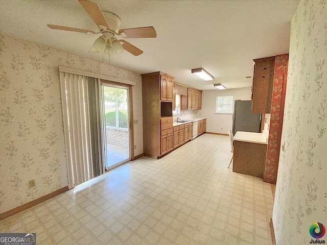 kitchen with light floors, light countertops, freestanding refrigerator, baseboards, and wallpapered walls