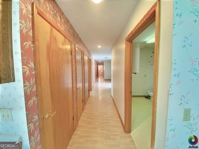 corridor with wallpapered walls, light wood-style flooring, and baseboards