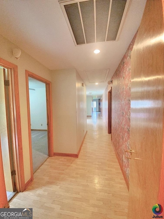 hall with baseboards, visible vents, and light wood finished floors