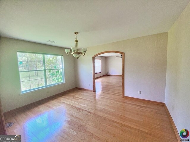 spare room featuring a notable chandelier and light hardwood / wood-style flooring