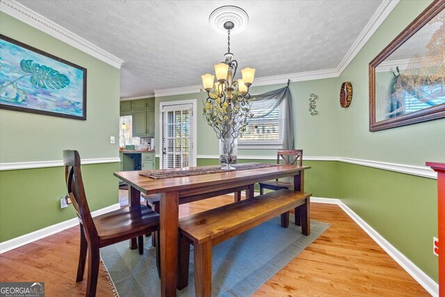 dining space featuring a notable chandelier, crown molding, hardwood / wood-style floors, and a textured ceiling