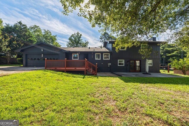 view of front facade with a garage, a deck, and a front lawn