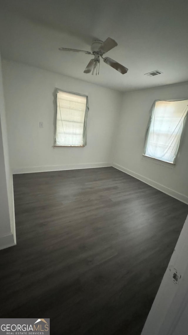 spare room with dark hardwood / wood-style floors, ceiling fan, and a wealth of natural light