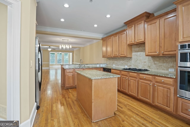 kitchen with a center island, ceiling fan, kitchen peninsula, light hardwood / wood-style floors, and light stone counters