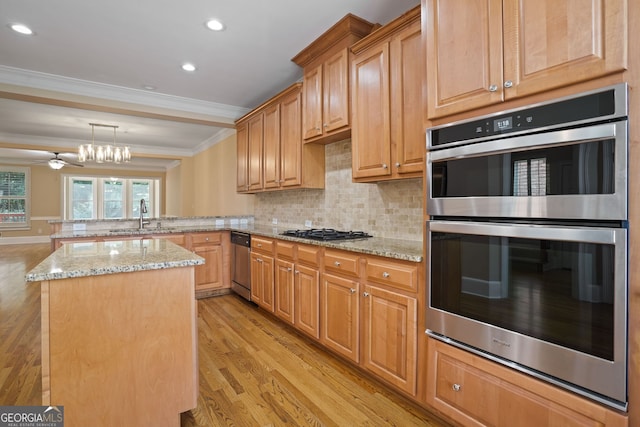 kitchen featuring appliances with stainless steel finishes, crown molding, light wood-type flooring, and kitchen peninsula