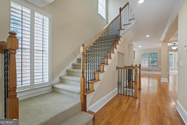 staircase with light hardwood / wood-style flooring, crown molding, and ceiling fan