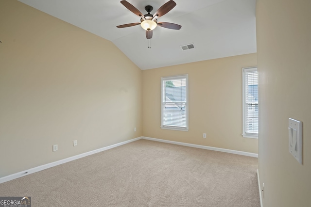 spare room with ceiling fan, lofted ceiling, and light colored carpet