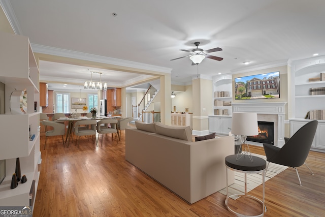 living room featuring built in features, a premium fireplace, ornamental molding, and light hardwood / wood-style floors