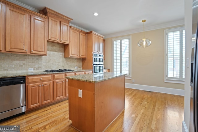 kitchen featuring appliances with stainless steel finishes, light wood-type flooring, light stone counters, and a healthy amount of sunlight