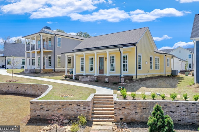 view of front of house featuring a front yard, a balcony, roof with shingles, a porch, and central air condition unit