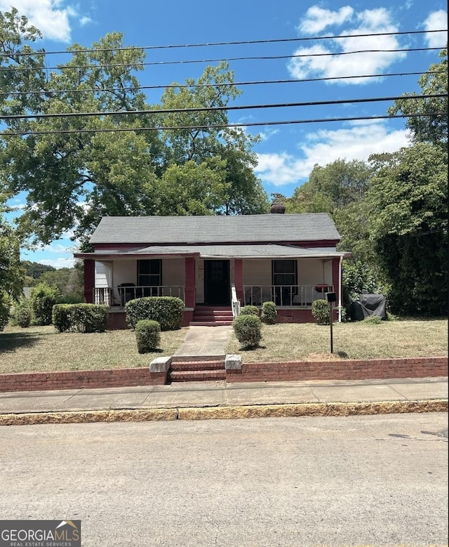 view of front of property featuring solar panels, covered porch, and a front yard