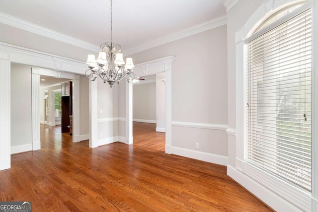 unfurnished dining area with ornamental molding, an inviting chandelier, and hardwood / wood-style flooring