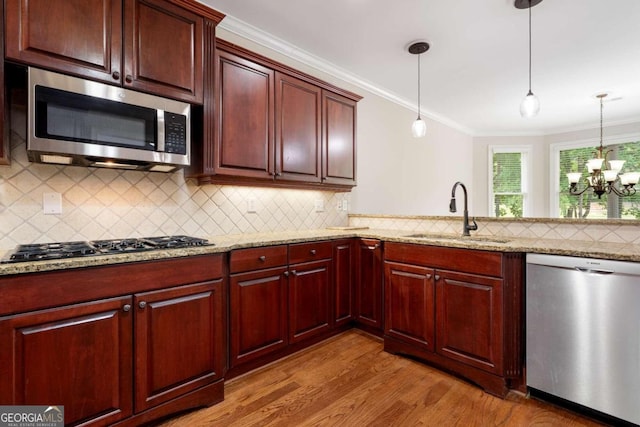 kitchen featuring an inviting chandelier, hanging light fixtures, appliances with stainless steel finishes, wood-type flooring, and sink