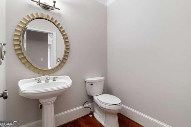 bathroom featuring ornamental molding, wood-type flooring, and toilet