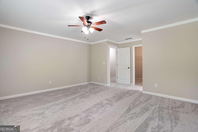 empty room with carpet floors, crown molding, and ceiling fan