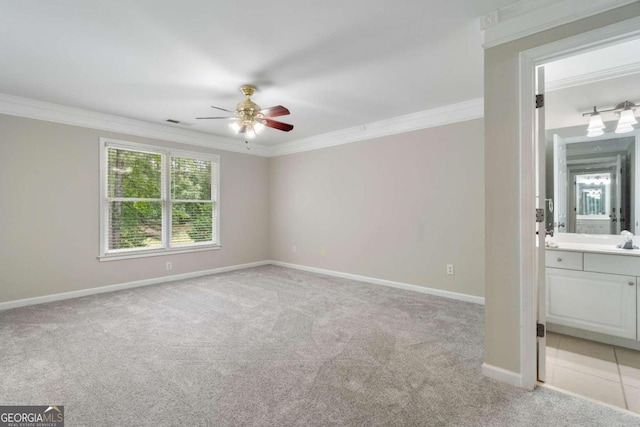 interior space featuring connected bathroom, ceiling fan, crown molding, light carpet, and sink