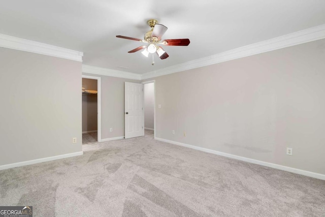 unfurnished bedroom featuring ornamental molding, carpet flooring, ceiling fan, and a walk in closet