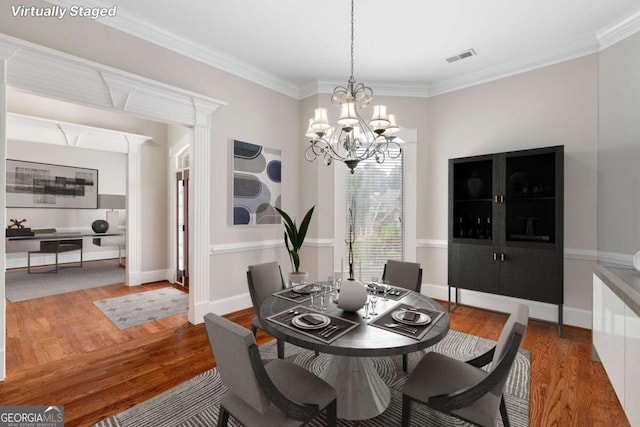 dining space with an inviting chandelier, wood-type flooring, and crown molding