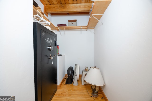 walk in closet with beamed ceiling and light hardwood / wood-style floors