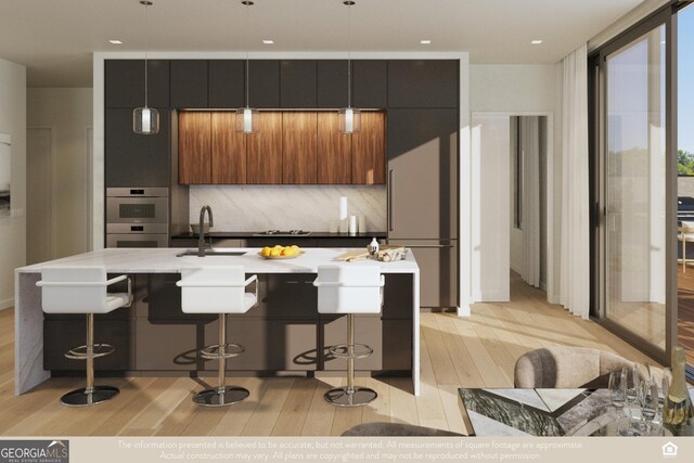 kitchen featuring high end fridge, sink, a breakfast bar area, and an island with sink