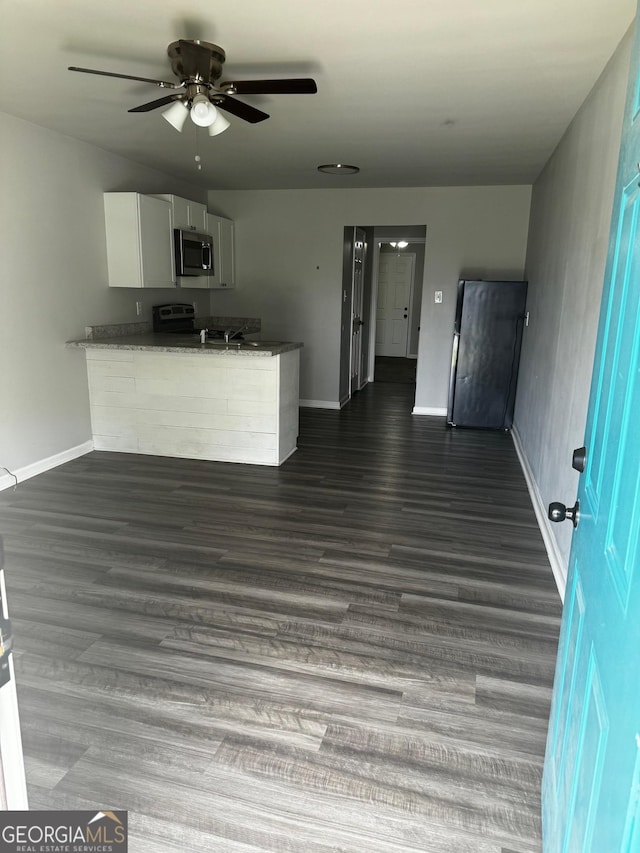 kitchen featuring ceiling fan, dark wood-type flooring, dark stone countertops, white cabinets, and range