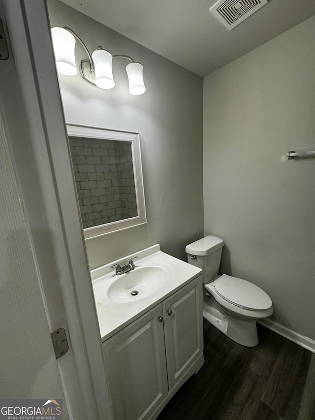 bathroom with wood-type flooring, vanity, and toilet