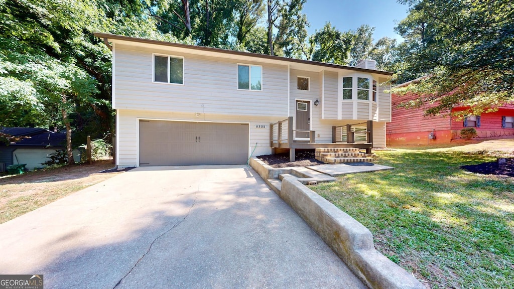 5332 Zachary Dr, Stone Mountain, GA 30083 - raised ranch featuring a garage, concrete driveway, a front lawn, and a chimney