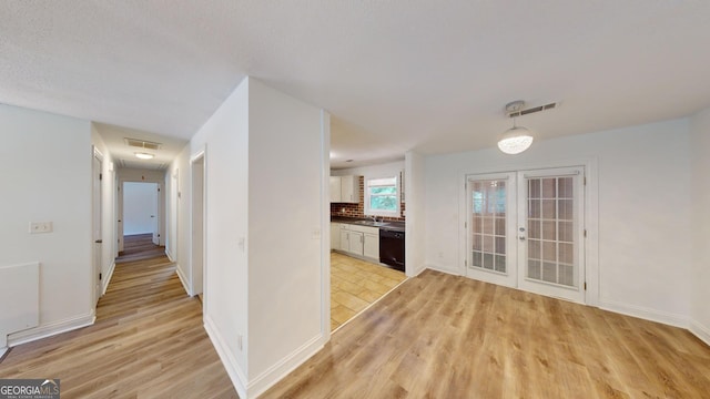 corridor with sink, french doors, and light tile patterned floors