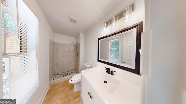 bathroom featuring tiled shower, vanity, tile patterned flooring, and toilet