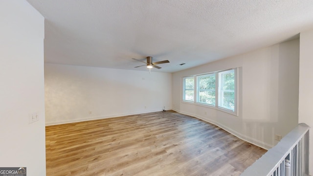 spare room with light hardwood / wood-style floors, a textured ceiling, and ceiling fan