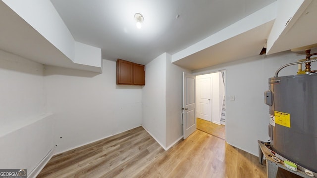 basement featuring light hardwood / wood-style floors and electric water heater