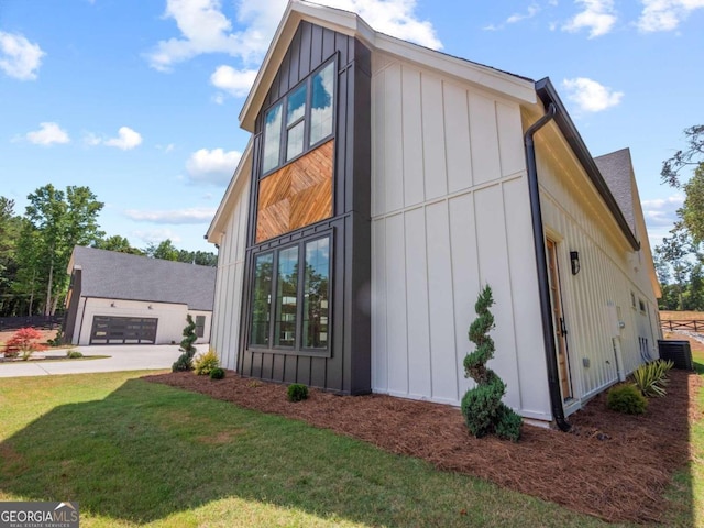 view of side of property with a garage, a yard, and central AC