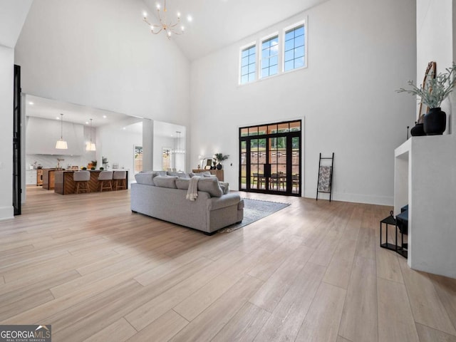 living room with a high ceiling, light hardwood / wood-style floors, and an inviting chandelier